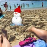 Piedi sulla sabbia e pupazzo di neve in primo piano, che mostra il clima caldo di Gran Canaria a gennaio.
