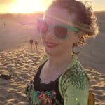 Donna sorridente che indossa occhiali da sole sulle dune di Maspalomas, Gran Canaria a gennaio.