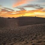 Sagome di persone su una duna che guardano il tramonto a Maspalomas, Gran Canaria a gennaio.