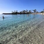 Primo piano sull'acqua turchese e cristallina di Playa Anfi del Mar a Gran Canaria con bagnanti che entrano in acqua a gennaio.