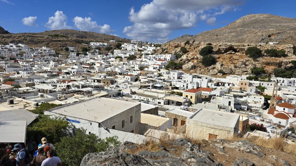 Lindos, Rodi: Guida Completa su Cosa Vedere, Acropoli e Spiagge del Villaggio Bianco 1 Villaggio di Lindos a Rodi visto dall'alto, durante la discesa dall'Acropoli. Si vedono le tipiche case bianche addossate l'una all'altra e le colline rocciose brulle circostanti.