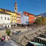 Il caratteristico lungolago di Ascona, con le sue case colorate affacciate sull'acqua e le montagne sullo sfondo.