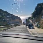 Vista dal cruscotto di un'auto a noleggio, in una mattina di inizio gennaio, sulla strada che porta alla spiaggia di Benagil in Algarve. L'immagine simboleggia la libertà di esplorazione in auto, essenziale per il viaggio invernale.