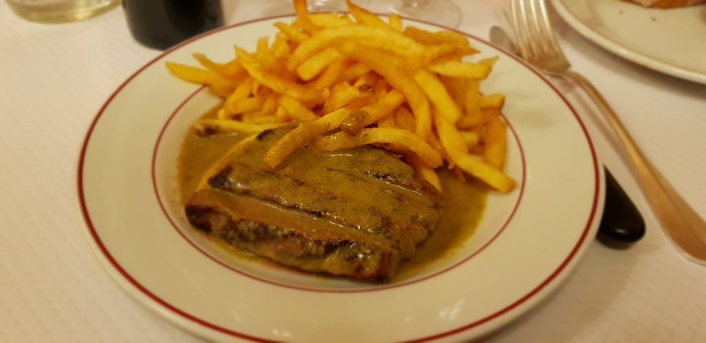 A classic plate of Entrecôte steak with thin French fries (Steak Frites), a must-try gastronomic delight in Paris.
