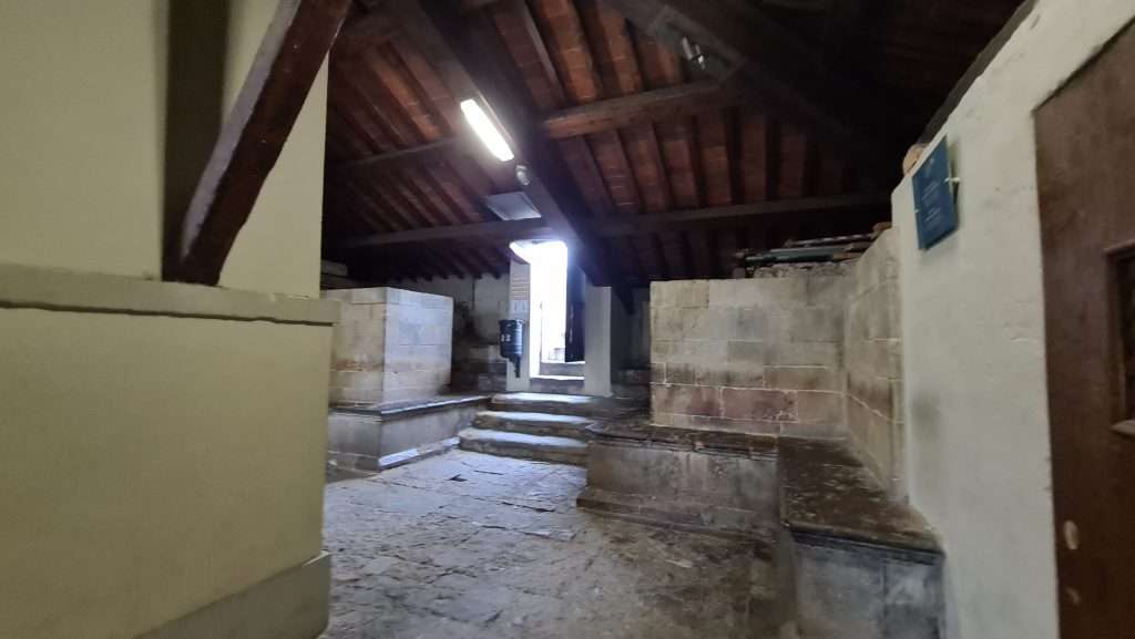 Interior view of the transition and resting space inside Giotto's Bell Tower in Florence. Visitors are seated, taking a break before climbing the final steps leading to the outdoor panoramic viewing corridor.