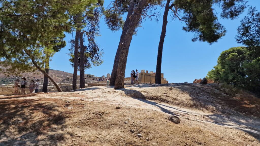 Visitors resting under the only available tree shade outside Knossos Palace to escape the intense summer heat.