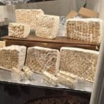 Display of large, rustic blocks of artisanal nougat (Torrone), showing both pistachio and hazelnut varieties at a vendor stall in Cremona.