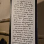 Close-up of a bilingual information panel for the Sala della Consulta in Cremona's Town Hall, showing Italian text in a large font and English translation below.