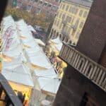 Elevated view showing multiple rows of white vendor stalls spreading across a central square during the Cremona Torrone Festival, with the Torrazzo visible in the background.