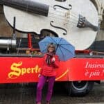 Ila standing by a Sperlari truck carrying a giant white violin replica during the Cremona Torrone Festival.
