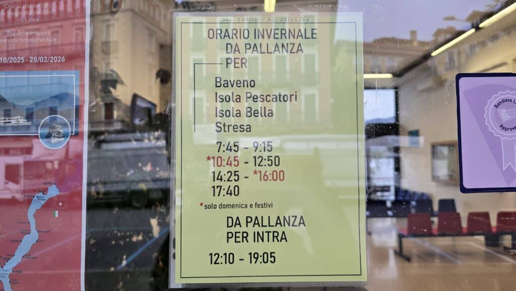 Photograph of the Lake Maggiore official boat service timetable board displayed at a Verbania ferry stop. The schedule indicates reduced service frequency for island and inter-town travel, valid specifically from November to March (the low season).