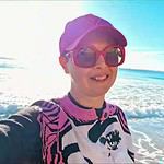 a woman wearing pink hat and sunglasses taking a selfie on a beach in a beach in the Algarve in winter