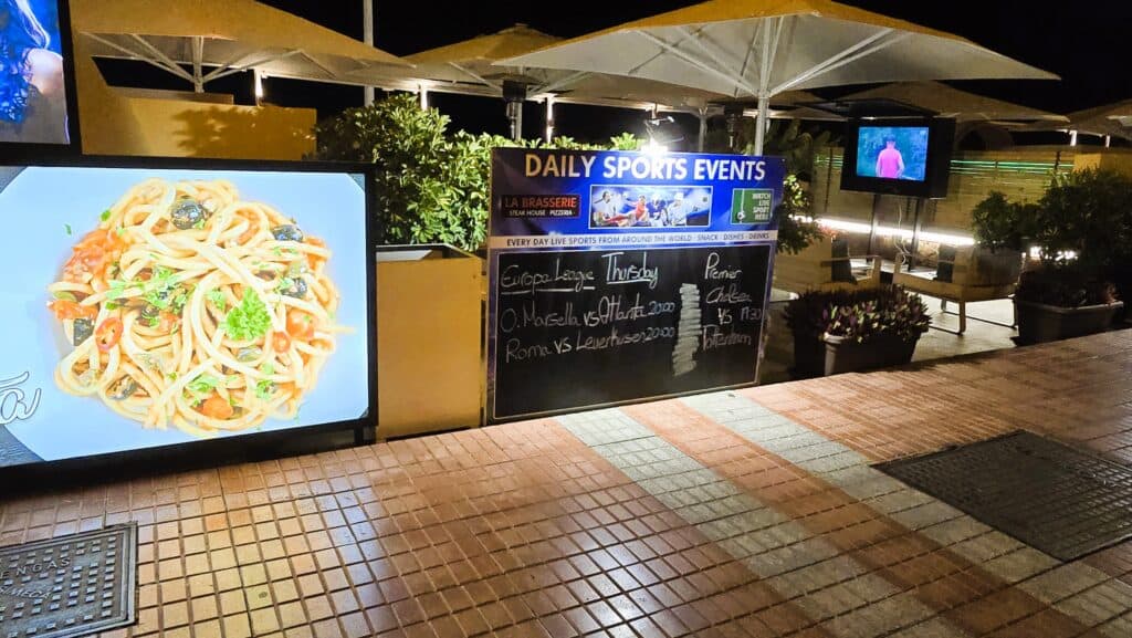 Tenerife Nightlife Expert Guide: How to Find Your Perfect Bar & The Canary Islands Vibe 4 Chalkboard schedule displayed outside a bar in Tenerife showing live sports and music timings.
