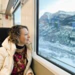 Ila, the article's author, relaxing and enjoying the snow-covered Alpine view from the large window of the Green Train.