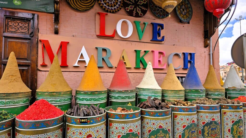 Marrakech in 3 Days: Culture, Souks & Thrilling Desert Quad Biking! 1 "LOVE MARRAKECH" sign above a display of colorful spices and goods in a traditional Moroccan market.