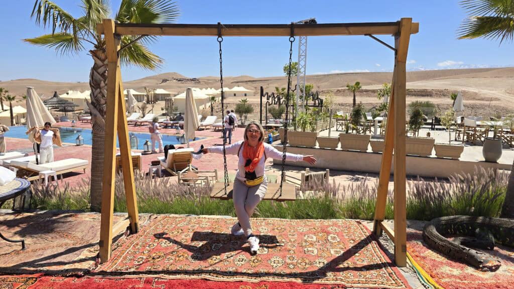 Marrakech Quad Biking: Thrills, Oasis Luxury & The City's Hidden Contrast 7 Ila relaxing on a swing at the stunning desert oasis resort, with a swimming pool and traditional tents visible in the background.