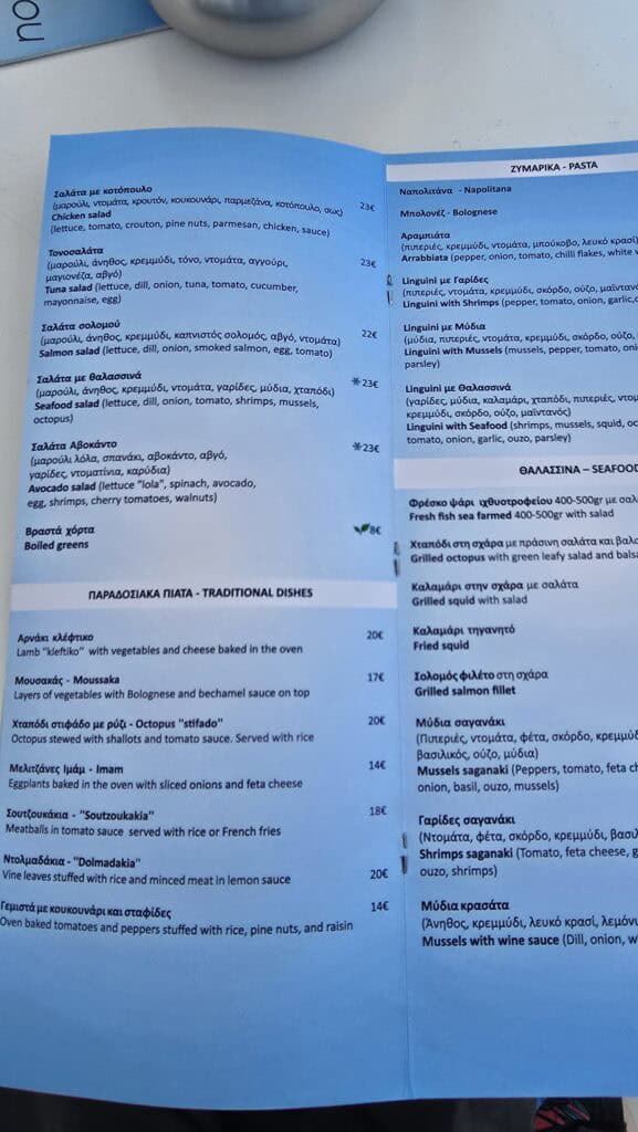 Cavo Psarou Mykonos restaurant menu page showing prices for salads (€18-€23), traditional Greek dishes like Moussaka (€17), and main seafood/pasta options like Grilled Salmon Fillet (€26).