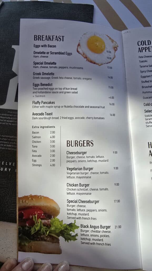 Your Guide to Paradise Mykonos: Is It a Party Beach or a Relaxing Escape? 2 The breakfast menu at Tropicana, Paradise Beach, showing prices for eggs, pancakes, and burgers in 2025.