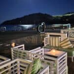Elegant beach bar at the Lindos 5-star Bay Hotel on Paralia Vlicha at night, showing cocktails under the moonlight.
