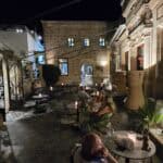 Interior of the elegant Colossas Bar in Lindos Old Town, showing people enjoying sophisticated drinks and the historic atmosphere at night.