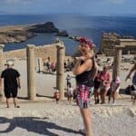 Ancient ruins with tourists exploring, scenic coastal views, and clear blue skies.
