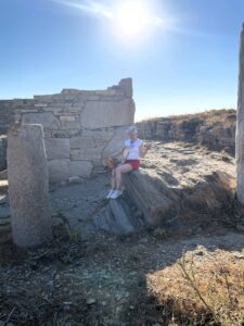 Ila resting with a friendly cat on the ancient ruins in Delos, Mykonos historical day trip.