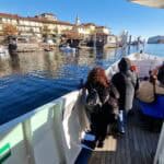 View from the ferry deck of Isola Pescatori (Fisherman's Island) in late December, showing passengers on board and the village, proving the Lake Maggiore boat tour runs year-round.