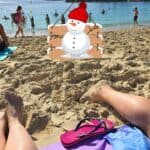 First-person view of feet and a snowman graphic on a sunny Gran Canaria beach in January.
