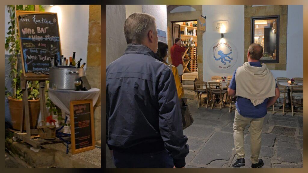 Kava Kantina wine bar and store in Lindos at night, showing wine tasting sign and bottles inside the shop entrance