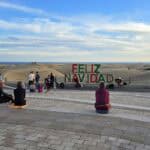 Maspalomas dunes with people and a "Feliz Navidad" sign in Gran Canaria in January.