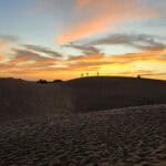 Silhouettes of people on a sand dune watching the sunset in Maspalomas, Gran Canaria in January.