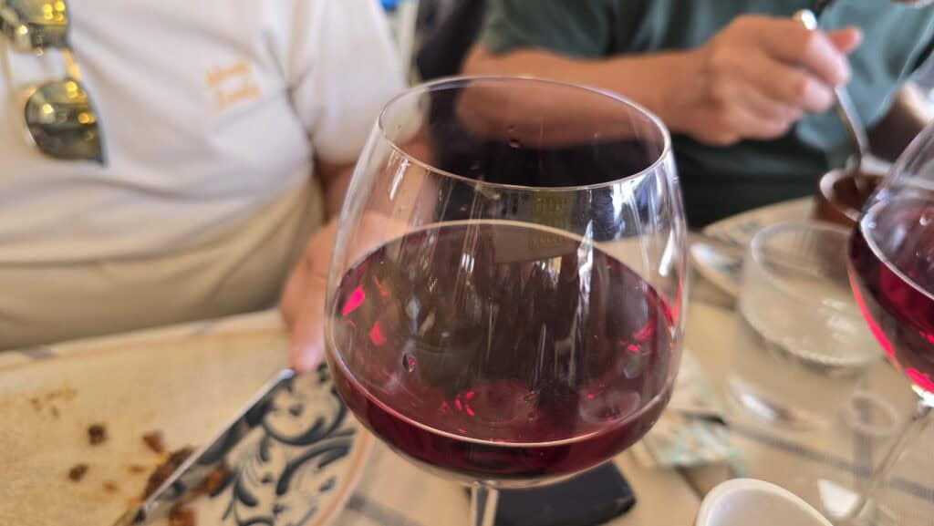 Close-up of a glass of bright ruby red Greek wine in Rhodes, showing its translucent color that indicates a light body and fresh style.