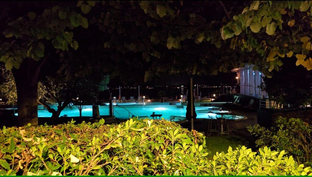 Illuminated outdoor thermal pool at Aquaria Spa Sirmione at night with steam rising off the water