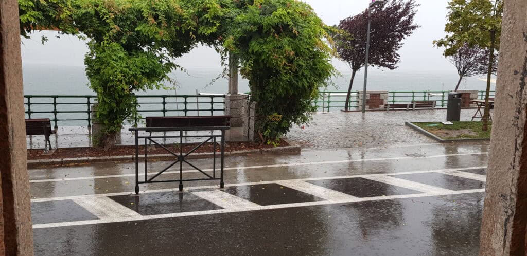 View of Lake Maggiore from a lakeside bar in Arona during a rainy or cloudy day, showing the peaceful atmosphere