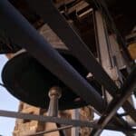Close-up view of the massive Campanone bell and structural framework inside Bergamo's historic Civic Tower, known for the 10 PM chimes tradition.