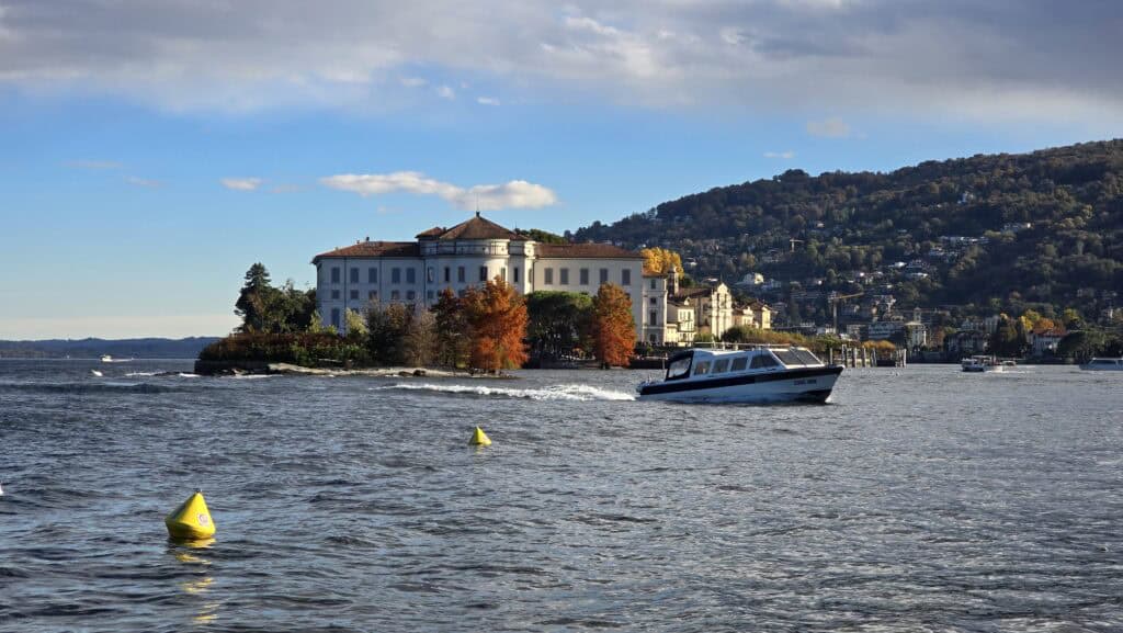 Isola Bella and Palazzo Borromeo on Lake Maggiore, viewed from Isola Pescatori, showcasing the autumnal foliage colors.
