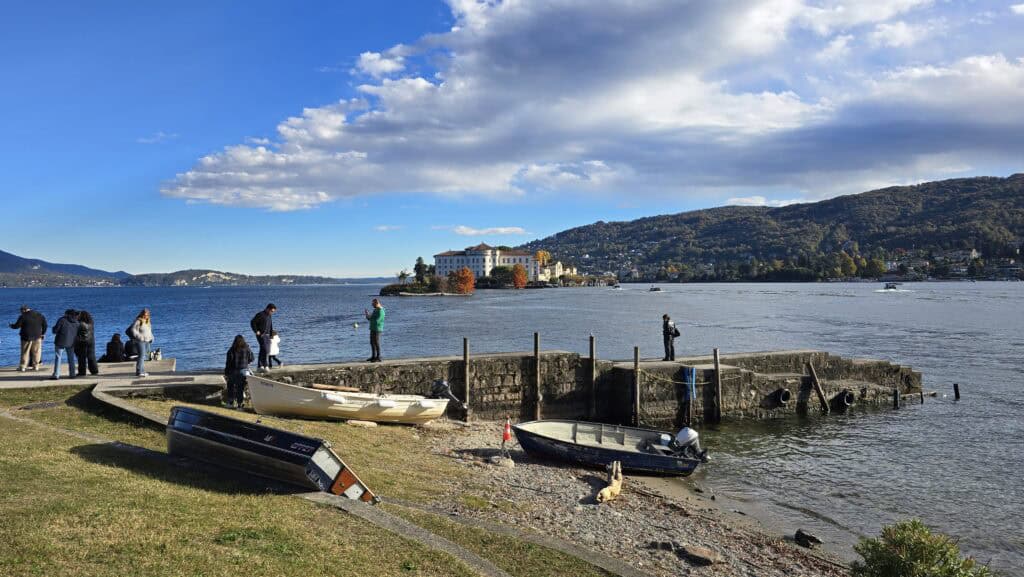 Tourists gathered on Isola Pescatori's dock taking photos of Isola Bella, providing an accurate visual perspective of the real distance and proportion between the two islands.