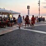 Wide illuminated lakeside promenade (Lungolago) in Lazise, Lake Garda, showing shops and restaurants at night
