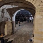The historic stone archway of the Venetian Walls (near Porta San Giacomo) overlooking the illuminated Lower Town at night.