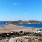 Aerial view of Prasonisi beach showing the small, concentrated services area (tavernas, shops) in contrast to the vast, free isthmus.
