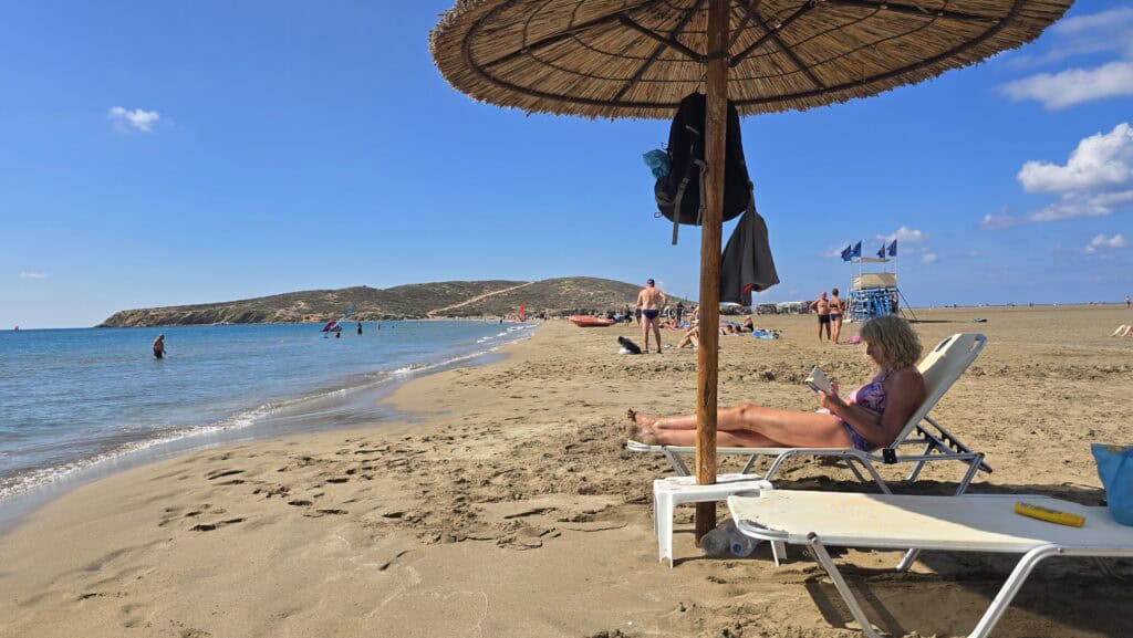 Prasonisi Rhodes: Where Two Seas Meet (2026 Planning Guide & Prices) 5 Prasonisi sunbed set under a straw umbrella on the calm Mediterranean side. Emphasizing the vast, surrounding free beach area.