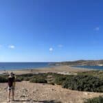 Traveler taking a photo from the essential panoramic viewpoint at Prasonisi, capturing the entire isthmus where the two seas meet.