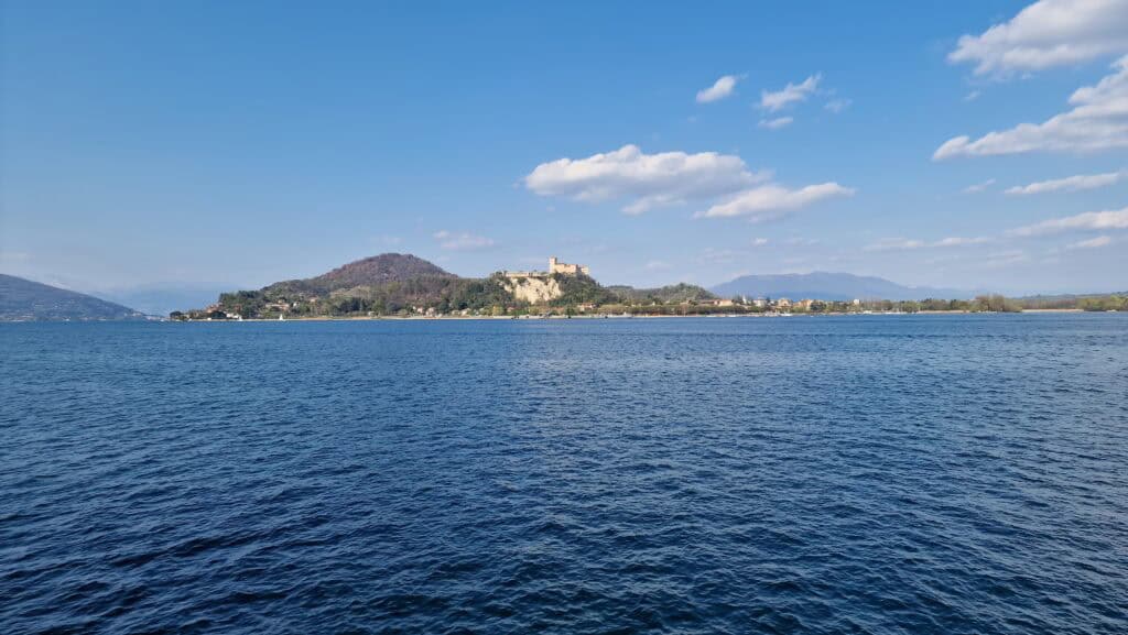 View of the majestic Rocca di Angera castle across Lake Maggiore, taken from the Arona lakeside promenade.