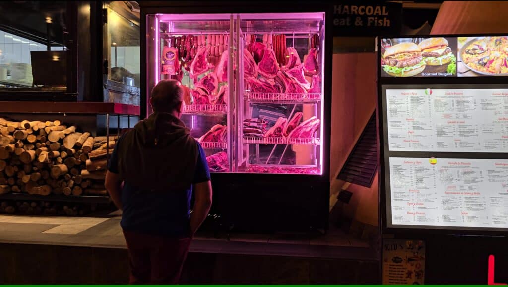 Menu showing large burgers and meat options in a Costa Adeje bar, catering to American and British tourists seeking familiar food alongside nightlife.