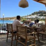 Almyra Restaurant in Lindos showing its elegant seaside location and outdoor seating, ideal for evening drinks or dinner with easy parking access.
