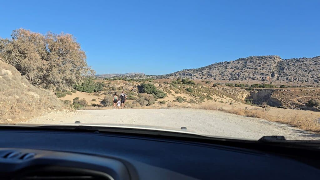 Unpaved but wide and well-maintained access road leading to Agathi Beach in Rhodes, showing the need for slight ground clearance.