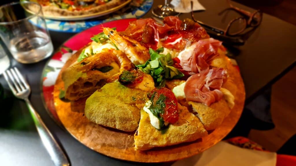 Gourmet pizza tasting platter with various toppings at Anima Romita restaurant in Crema, Italy, near the public gardens