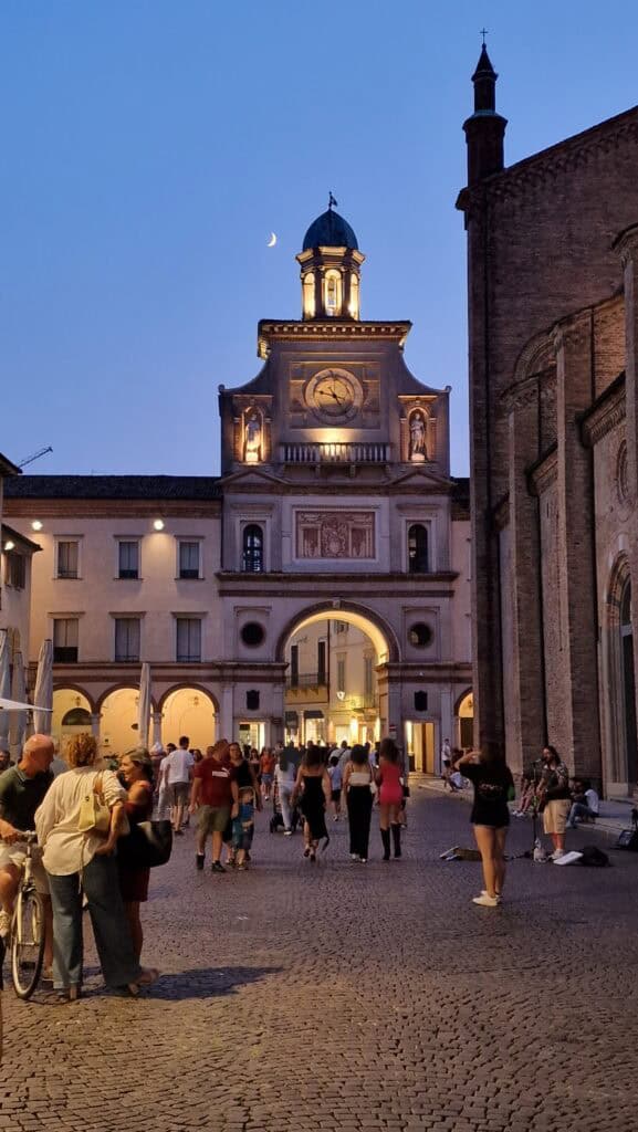 Iconic night view of Piazza Duomo Crema with the Torrazzo illuminated and a crescent moon visible above the archway