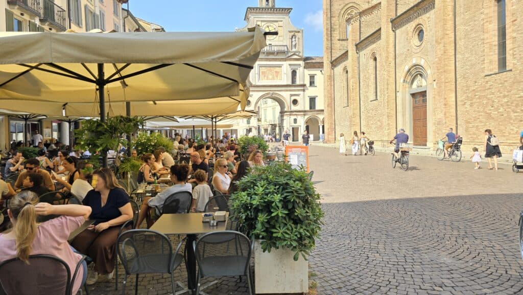People enjoying drinks and social life at cafes in Piazza Duomo, Crema, Italy, with bicycles parked nearby