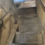 View of the steep, uneven, and narrow stone stairs inside Brunelleschi's Dome, highlighting the historic and irregular nature of the ascent path.